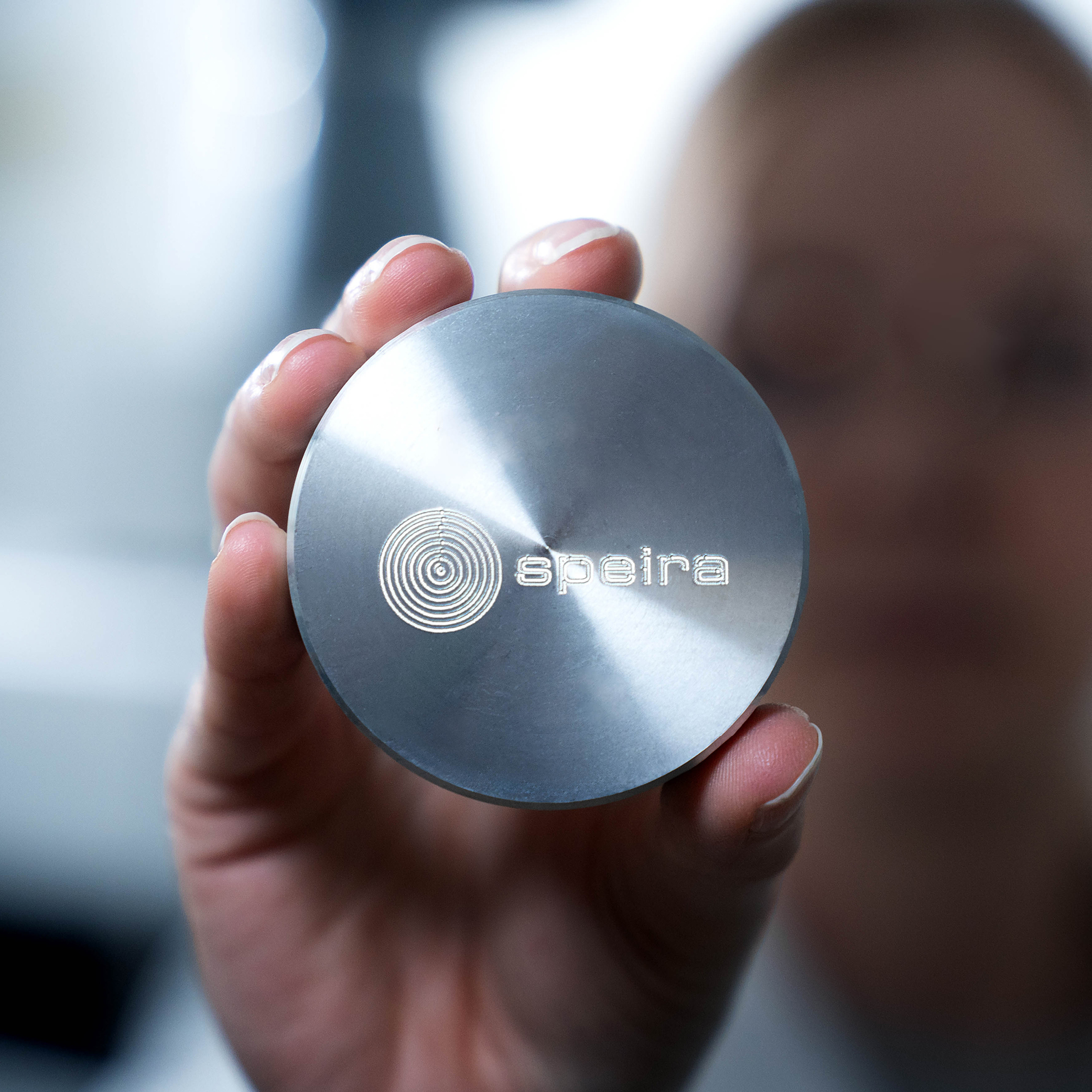 Eine Frau hält eine Speira-Aluminium-Referenzstandard-Metallscheibe in der Hand (OES/XRF-Probe)