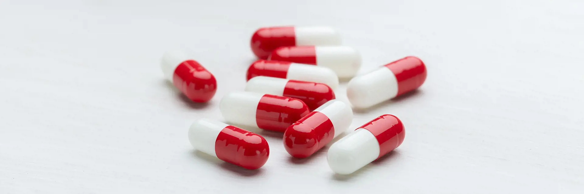 Red and white medicine capsules on a light grey background